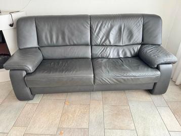 Grijze 3-zits leren bank met gebruikerssporen
