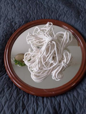 Grote ronde spiegel en dik macrame touw.