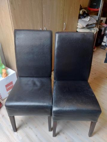 Drie zwarte leren stoelen met gebruikerssporen