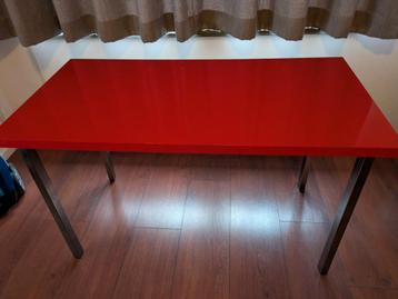 Mooi glans rood bureau met metaal grijze poten.