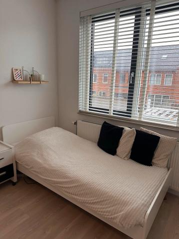 Wit eenpersoonsbed met matras en matrasbeschermer