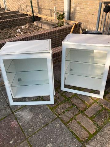 Twee witte wandkasten met glazen planken
