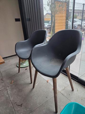 2 donkergrijze kuipstoelen met houten poten