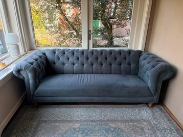 Blauwe stoffen bank met knopen en siernagels