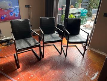 Drie zwarte stoelen met metalen frame