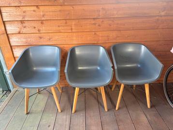 Drie grijze stoelen met houten poten