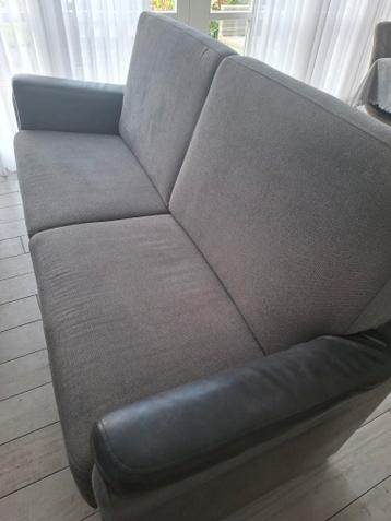 Grijze tweezitsbank met donkere armleuningen