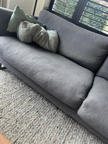 Grijze bank met kussens en puff