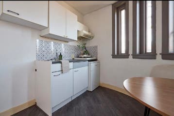 Compacte witte keuken met bovenkasten en koelkast