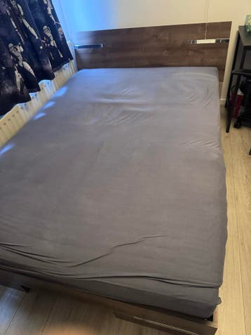 Tweepersoonsbed met houten hoofdbord