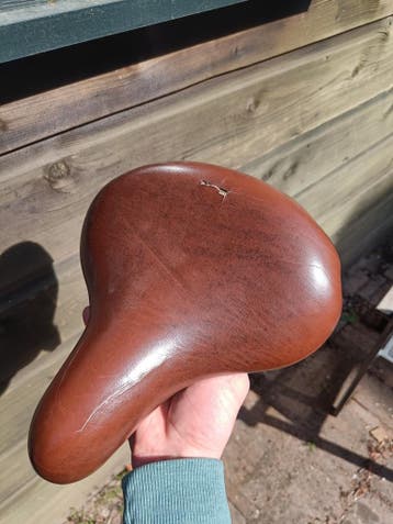 Bruin fietszadel met veren, kapot