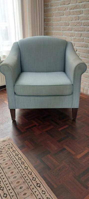 2 lichtblauwe fauteuils met gebruikerssporen op armleuningen