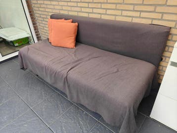 Donkergrijze slaapbank met oranje kussens