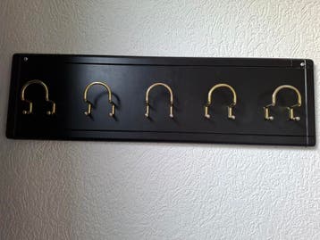 Zwarte kapstok met goudkleurige haken.