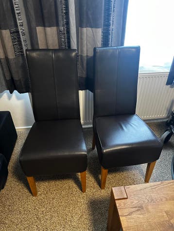 Twee donkerbruine eetkamerstoelen van leer