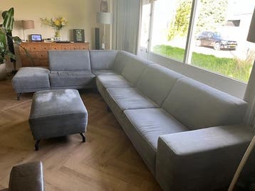 Grijze hoekbank met poef