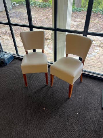 Twee crème stoelen met houten poten