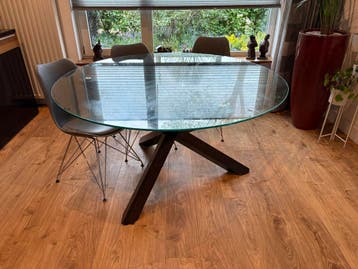 Ronde eettafel met glazen blad en zwart onderstel