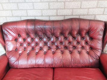 Donkerrode leren chesterfieldlook bank met gebruikerssporen