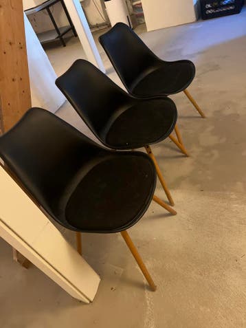 Drie zwarte stoelen met houten poten