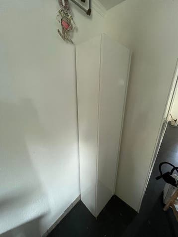 Witte smalle kast met glazen en houten planken