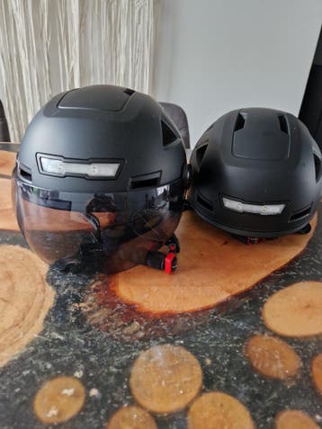 Twee zwarte fietshelmen, een met smokey vizier