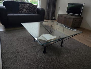 Glazen salontafel met zwarte metalen standaard