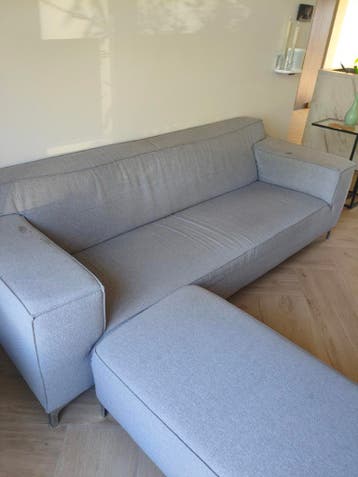 Comfortabele grijze bank met poef