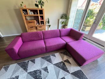 Comfortabele fuchsiakleurige hoekbank met hocker