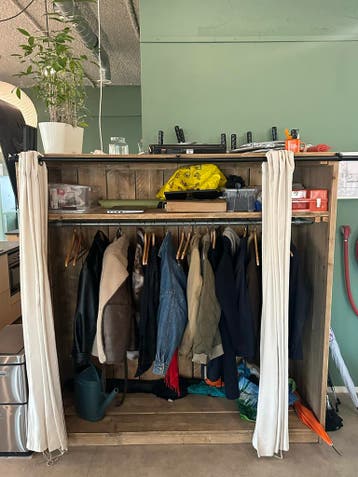 Houten garderobekast met roede en crèmekleurige gordijnen