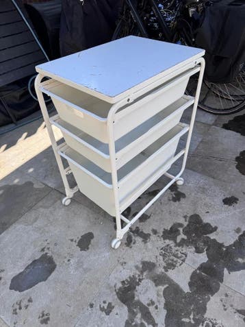 Witte trolley met lades en beschadigd blad