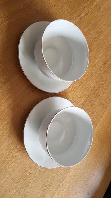 Twee witte kommen met gouden rand en schotels