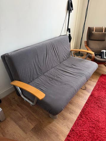 Comfortabele grijze slaapbank met houten armleuningen