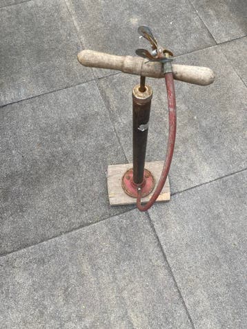 Oude fietspomp met houten handvat
