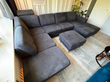 Grote grijze hoekbank met chaise longue en poef