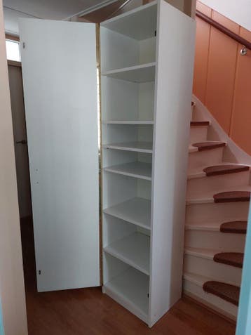 Witte smalle kast met planken en deur