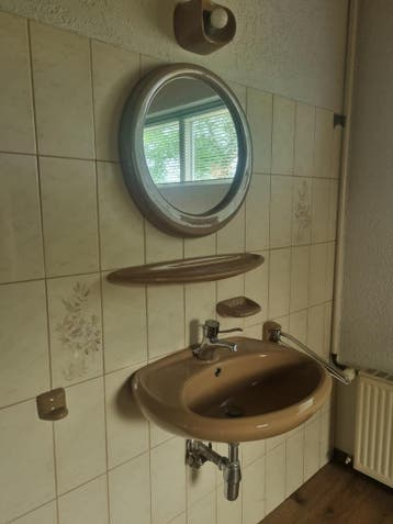 Vintage wastafel met spiegel en accessoires.