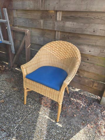 Comfortabele rieten stoel met blauw kussen