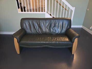 Compacte groene leren bank met houten accenten