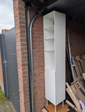 Witte hoge badkamerkast met glazen planken en deurtje