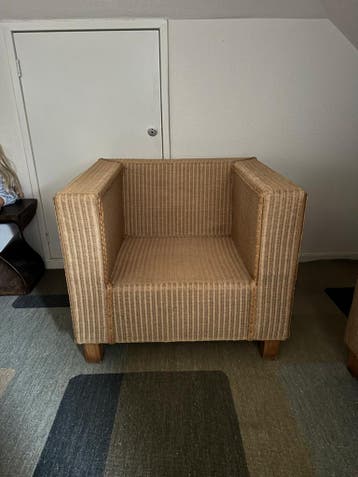 Comfortabele rotan fauteuil met rode kussens