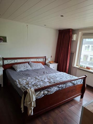 Tweepersoonsbed van donker hout met metalen details