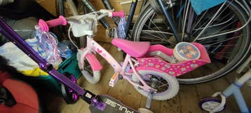 Roze kinderfiets met zijwieltjes en poppenzitje
