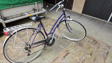 Paarse damesfiets met versnellingen en bagagedrager