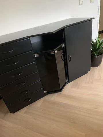 Zwart dressoir met laadjes en glasdeurtjes.