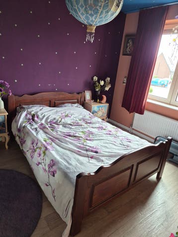 Houten tweepersoonsbed met sierlijk hoofdeinde