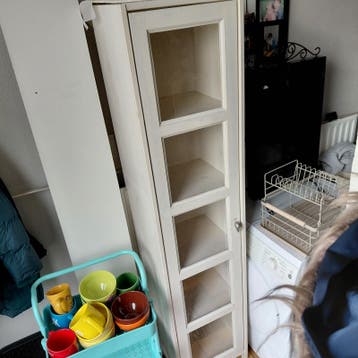 Smalle witte vitrinekast met glazen deuren