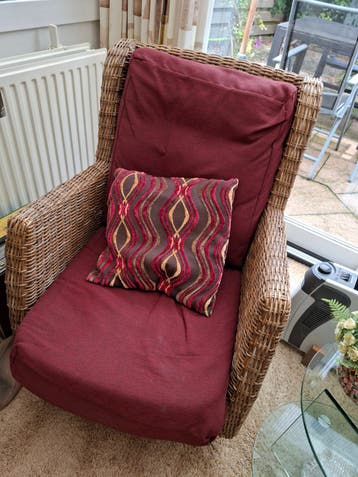 Comfortabele rotan fauteuil met bordeauxrode kussens