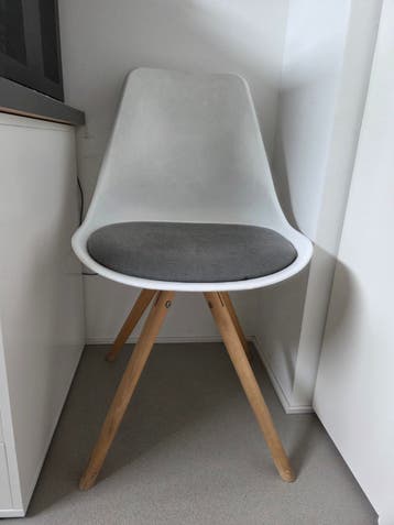 Moderne witte stoel met houten poten en grijs kussen