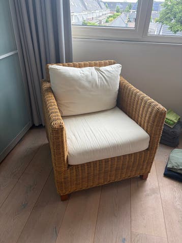 Comfortabele rotan fauteuil met crèmekleurige kussens
